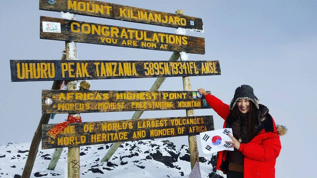 Climbers at Uhuru Peak sign on Mount Kilimanjaro